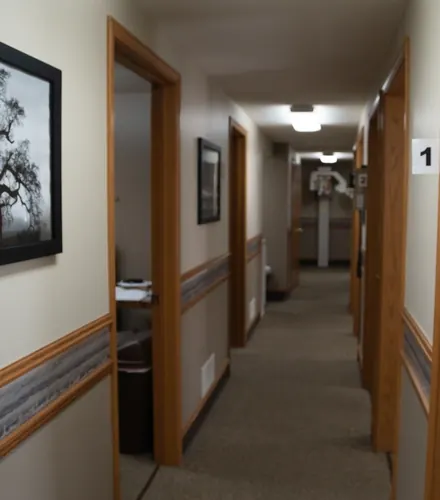 A corridor of numbered treatment rooms with framed photographs on the walls.