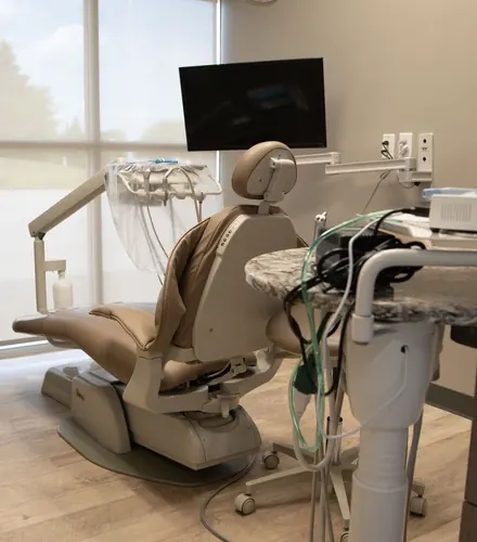A bright treatment room with a dental chair, a wall-mounted screen and a sign reading Smile.
