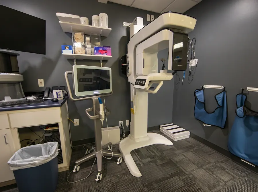 A cone beam CT imaging unit and its monitor in a Harrison Dental Group imaging room.